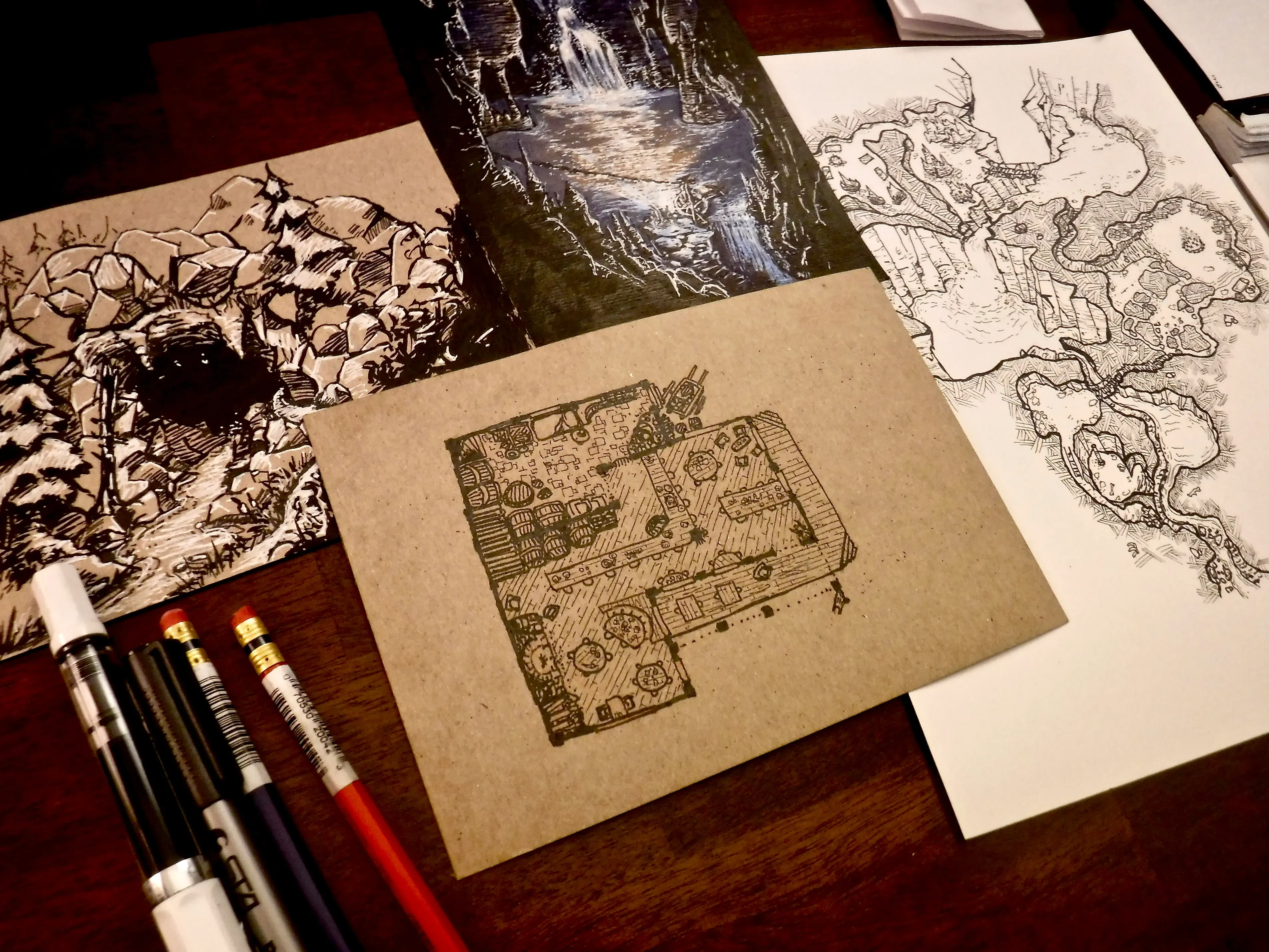A tabletop arrangement of hand-drawn fantasy maps and detailed ink illustrations